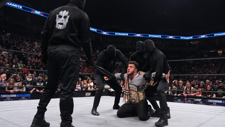 Three masked men dressed in all black attack MJF inside the AEW ring with a black baseball bat.