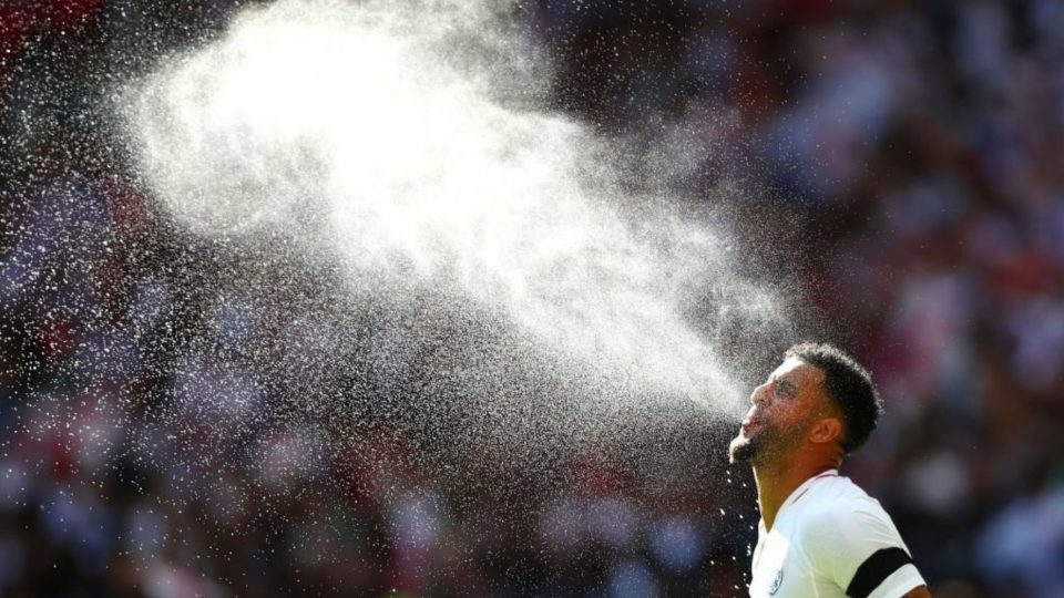 Manchester City player Kyle Walker spraying water into the air in Tottenham's home kit