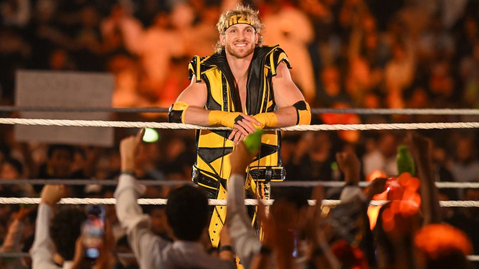 Logan Paul smiling whilst leaning on the ropes and looking out at the crowd at WWE Crown Jewel 2022
