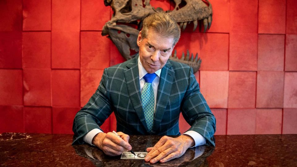 WWE CEO Vince McMahon In Front Of A Red Wall With A Dinosaur Skull
